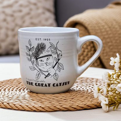 White mug with black cat illustration and text on a woven mat with flowers