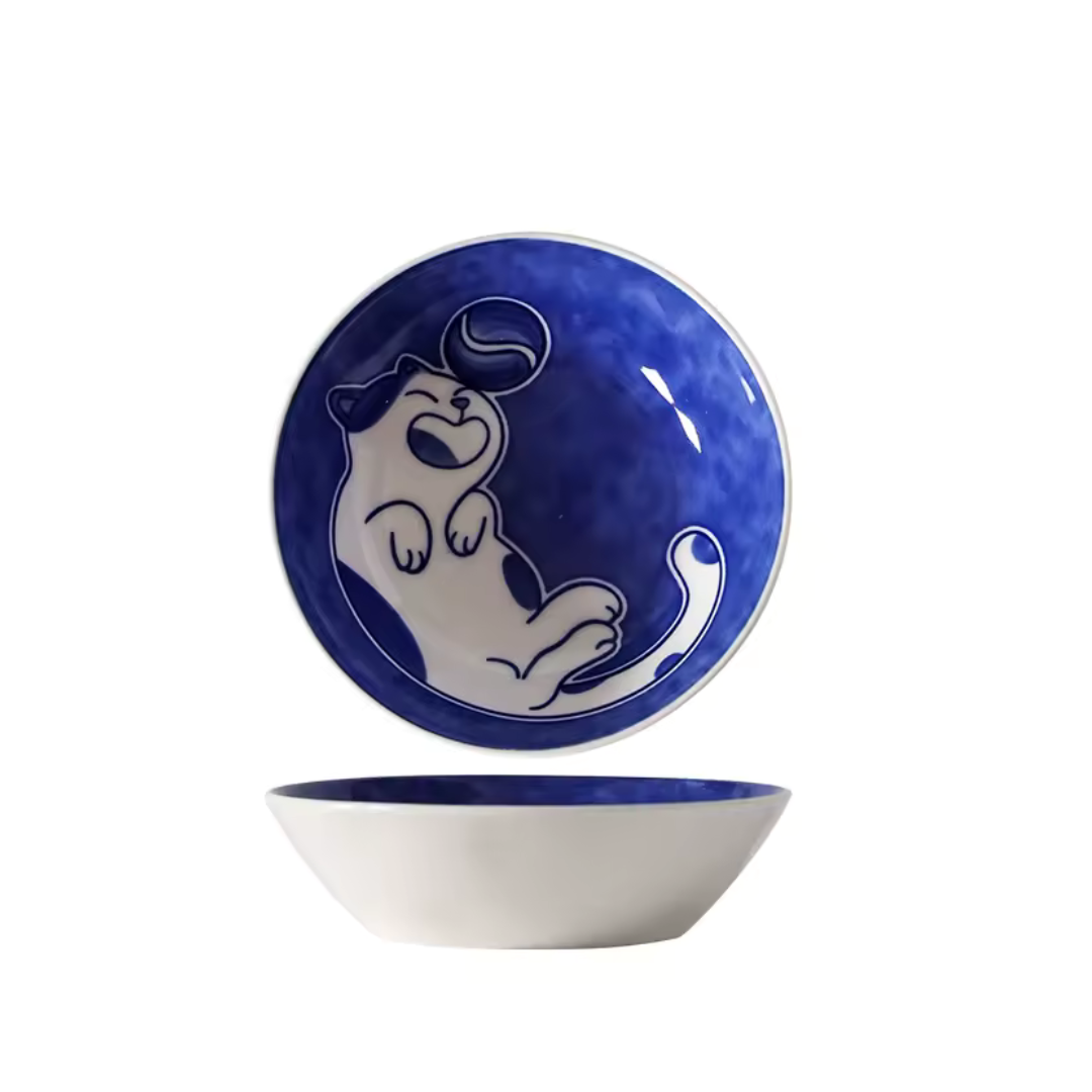 Ceramic bowl with blue rim and white interior, featuring a cartoon cat design on a white background. playing with a ball